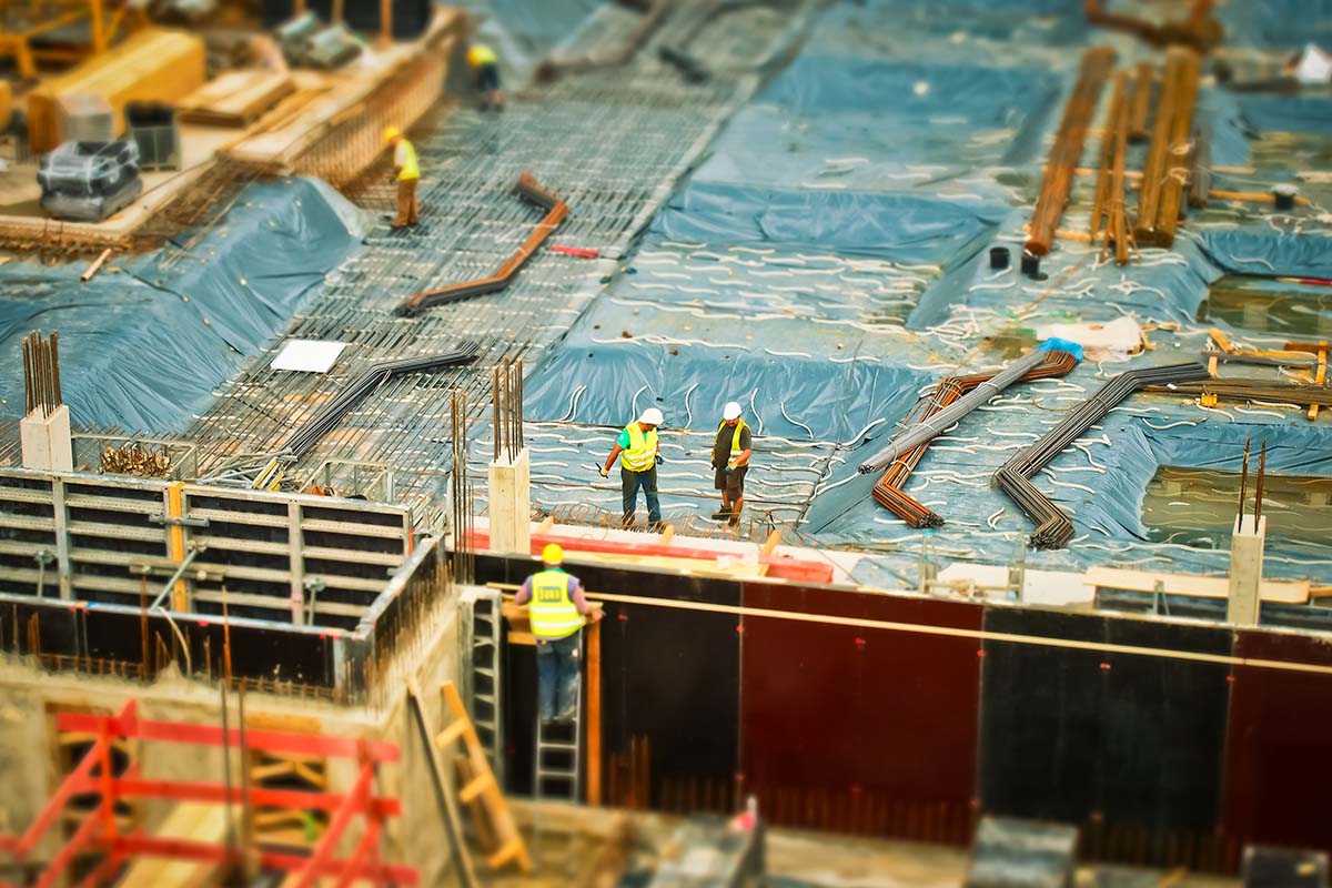 Large construction site with three workers.