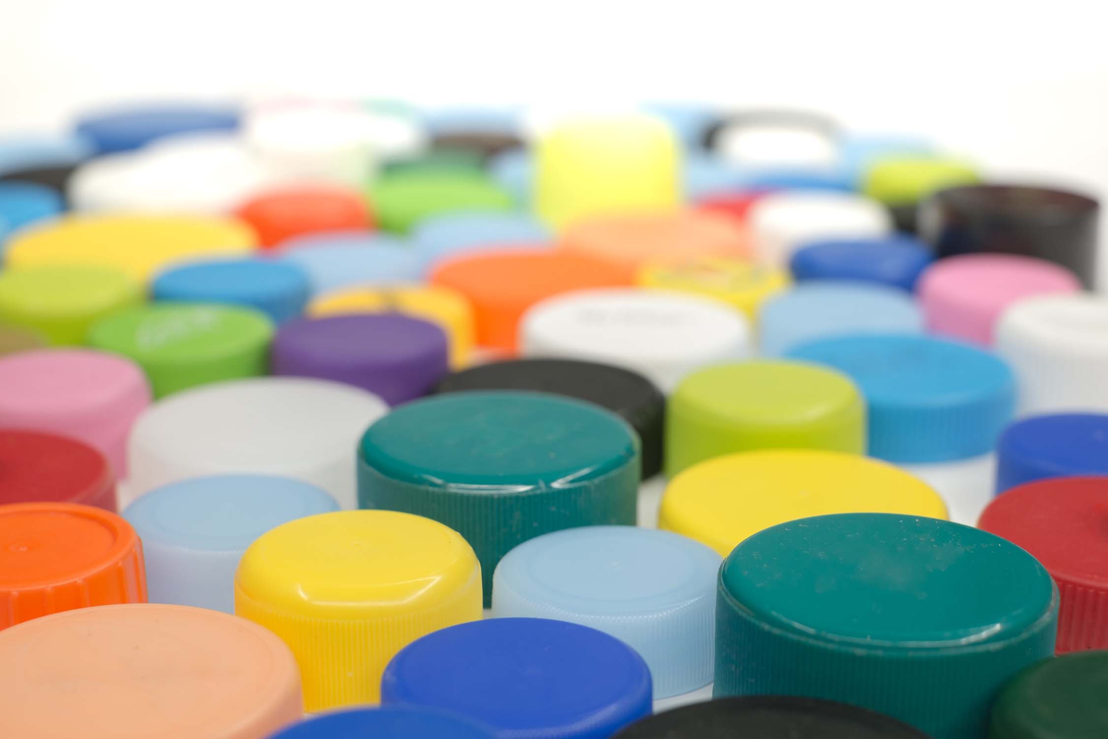 Over 50 multi-coloured spray paint lids and bottles.